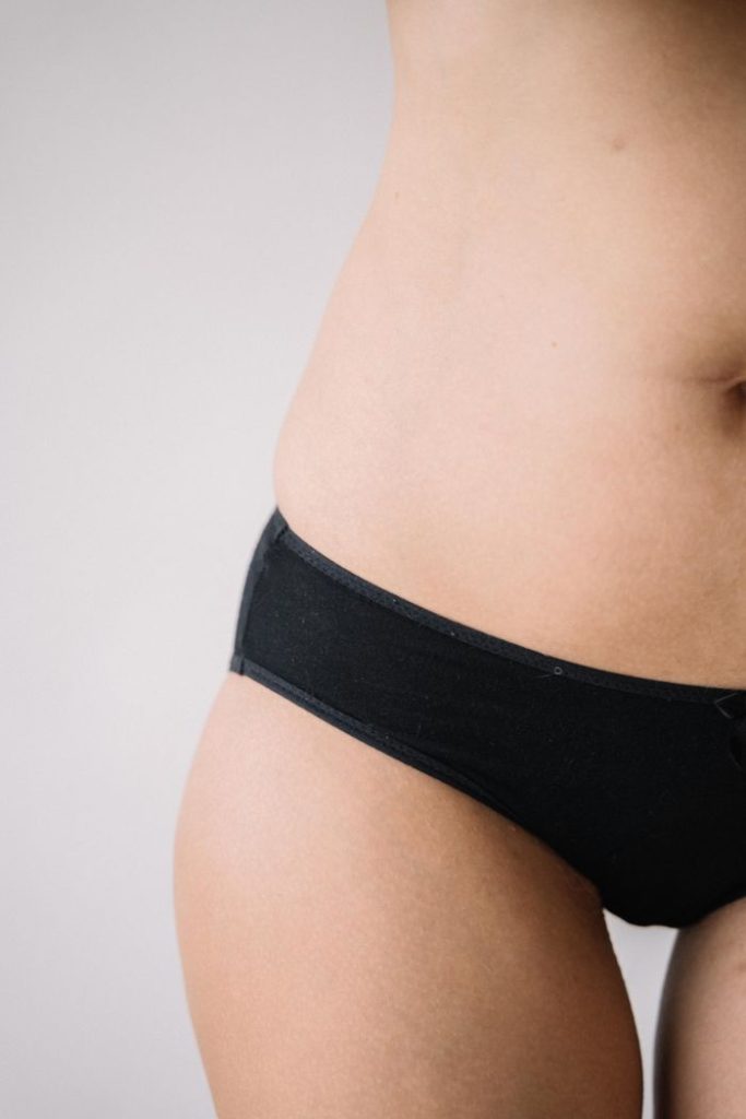 A close-up shot of a woman wearing black underwear, highlighting the hip area.