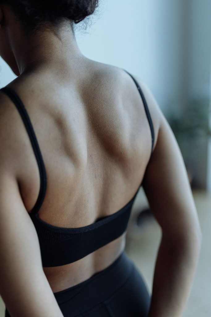 Close-up of a muscular woman's back wearing a sports bra, showcasing fitness and strength.