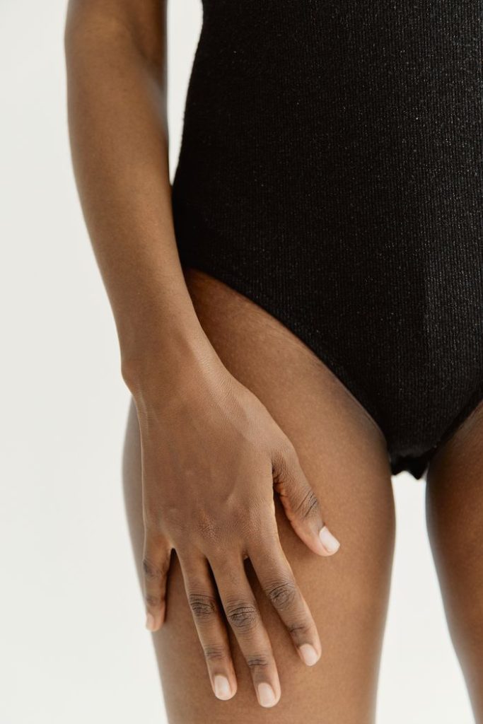 Elegant close-up of a woman's hand on shiny black fabric. Perfect for fashion and beauty themes.
